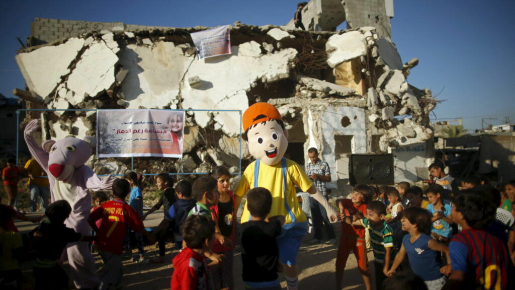 SMIL: Kostymekledde palestinere underholder barn på Gazastripen. I bakgrunnen et hus som ble ødelagt under krigen i fjor sommer. En stor andel av barna orådene som ble hardets rammet avkrigen sliter med mareritt, sengevæting og andre tegn på traume. Bildet er tatt tidliger ei juli.Foto: REUTERS/Mohammed Salem/ NTB Scanpix SMIL: Kostymekledde palestinere underholder barn på Gazastripen. I bakgrunnen et hus som ble ødelagt under krigen i fjor sommer. En stor andel av barna orådene som ble hardets rammet avkrigen sliter med mareritt, sengevæting og andre tegn på traume. Bildet er tatt tidliger ei juli.Foto: REUTERS/Mohammed Salem/ NTB Scanpix