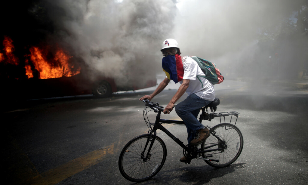 KAOS: En demonstrant sykler forbi en brennende bil midt i kaoset i Caracas i Venezuela i dag. Foto: REUTERS/Ueslei Marcelino/NTB Scanpix KAOS: En demonstrant sykler forbi en brennende bil midt i kaoset i Caracas i Venezuela i dag. Foto: REUTERS/Ueslei Marcelino/NTB Scanpix