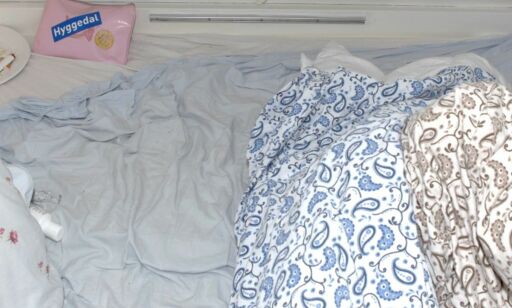 image: På et dolokk sitter en politibetjent. I badstua sitter Andrea. I en campingvogn sover tre menn