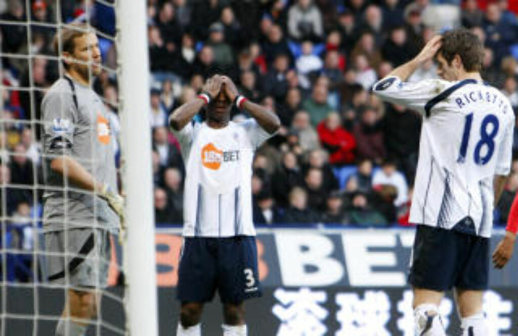 FORTVILELSE: Boltons Jlloyd Samuel tar seg til topplokket etter å ha satt ballen i eget mål. Foto: AP Photo/Tim Hales FORTVILELSE: Boltons Jlloyd Samuel tar seg til topplokket etter å ha satt ballen i eget mål. Foto: AP Photo/Tim Hales