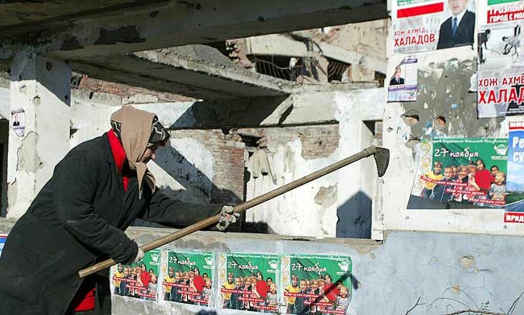 KRIGSHERJET: En kvinne arbeider ved et istykkerskutt hus, overklistret med valgpropaganda. Foto: Reuters/Scanpix KRIGSHERJET: En kvinne arbeider ved et istykkerskutt hus, overklistret med valgpropaganda. Foto: Reuters/Scanpix