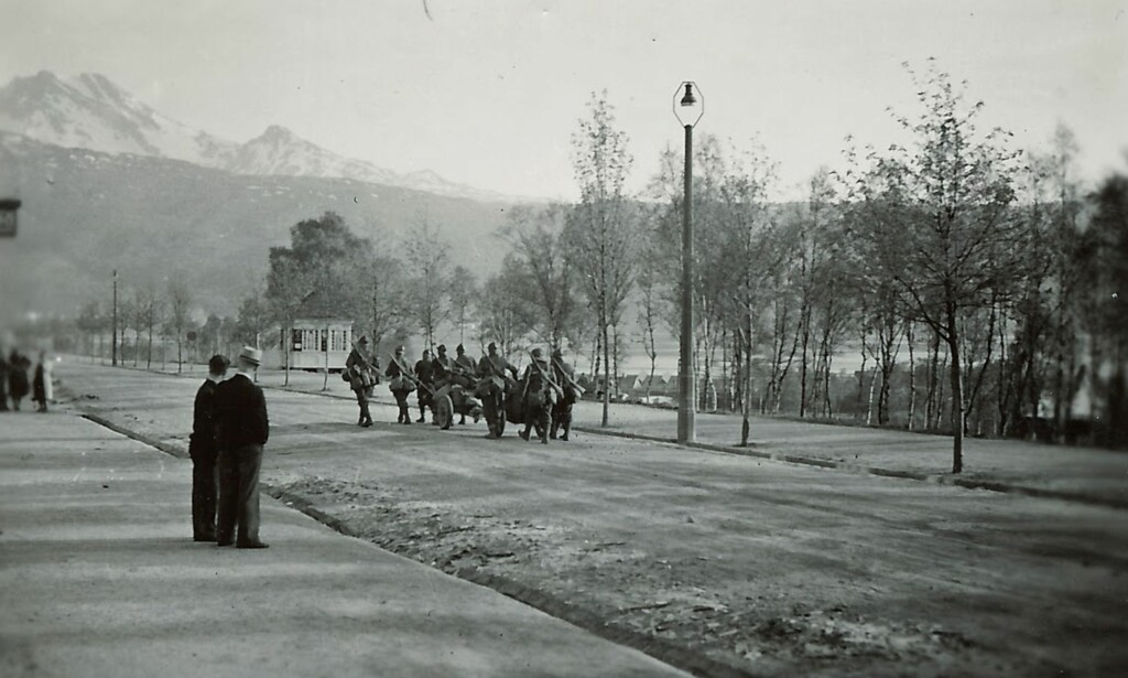 FRA NORD TIL SØR: Dette skal være tyske soldater som marsjerer i Narviks gater i 1940, ifølge notatene på baksiden av bildet marsjerer soldatene forbi jernbaneverkstedet i Narvik i 1940. Det lille, hvite huset i bakgrunnen skal være Hamnes blad- og tobakkiosk. Foto: Bildesamlingen til Kirsten Elisabeth Røsjorde FRA NORD TIL SØR: Dette skal være tyske soldater som marsjerer i Narviks gater i 1940, ifølge notatene på baksiden av bildet marsjerer soldatene forbi jernbaneverkstedet i Narvik i 1940. Det lille, hvite huset i bakgrunnen skal være Hamnes blad- og tobakkiosk. Foto: Bildesamlingen til Kirsten Elisabeth Røsjorde