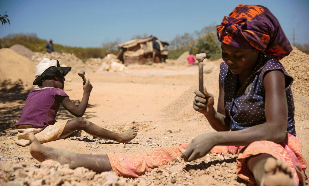 SYKDOM: Dette bildet fra mai 2016 viser et barn og en kvinne som knuser steiner hentet ut fra en koboltgruve i Lubumbashi, der gruvedriften skal ha ført til forurensning og sykdom. Foto: Junior Kannah / AFP / NTB Scanpix
