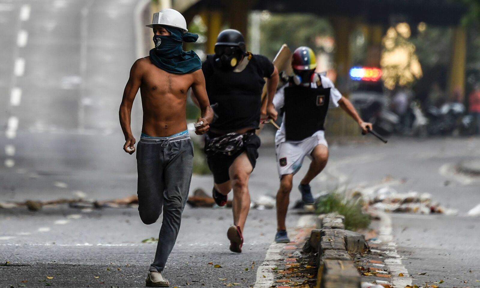 RØMMER: Her rømmer demonstranter fra opptøyer med politiet, etter en demonstrasjon mot president Nicolás Maduros regime. Foto: AFP / NTB Scanpix. RØMMER: Her rømmer demonstranter fra opptøyer med politiet, etter en demonstrasjon mot president Nicolás Maduros regime. Foto: AFP / NTB Scanpix.