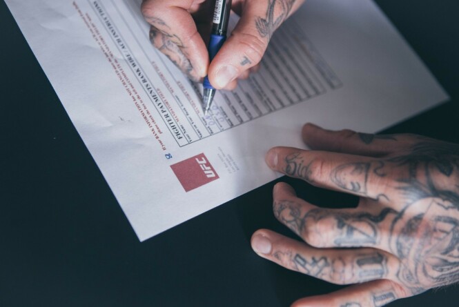 BLEKK OG TATOVERINGER: Kenneth Bergh setter sin signatur ved siden av UFC-logoen. Eventyret har startet. Foto: Frederic Esnault, Face2Face Creatives BLEKK OG TATOVERINGER: Kenneth Bergh setter sin signatur ved siden av UFC-logoen. Eventyret har startet. Foto: Frederic Esnault, Face2Face Creatives