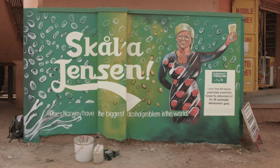 VEGGMALERI: «Skål'a Jensen!» er inspirert av en tale finansminister Siv Jensen holdt etter stortingsvalget i 2013. Maleriet er ett av flere som er malt på vegger i Uganda for å markere at Oljefondet bør trekke seg ut av alkoholindustrien. Foto: FORUT VEGGMALERI: «Skål'a Jensen!» er inspirert av en tale finansminister Siv Jensen holdt etter stortingsvalget i 2013. Maleriet er ett av flere som er malt på vegger i Uganda for å markere at Oljefondet bør trekke seg ut av alkoholindustrien. Foto: FORUT