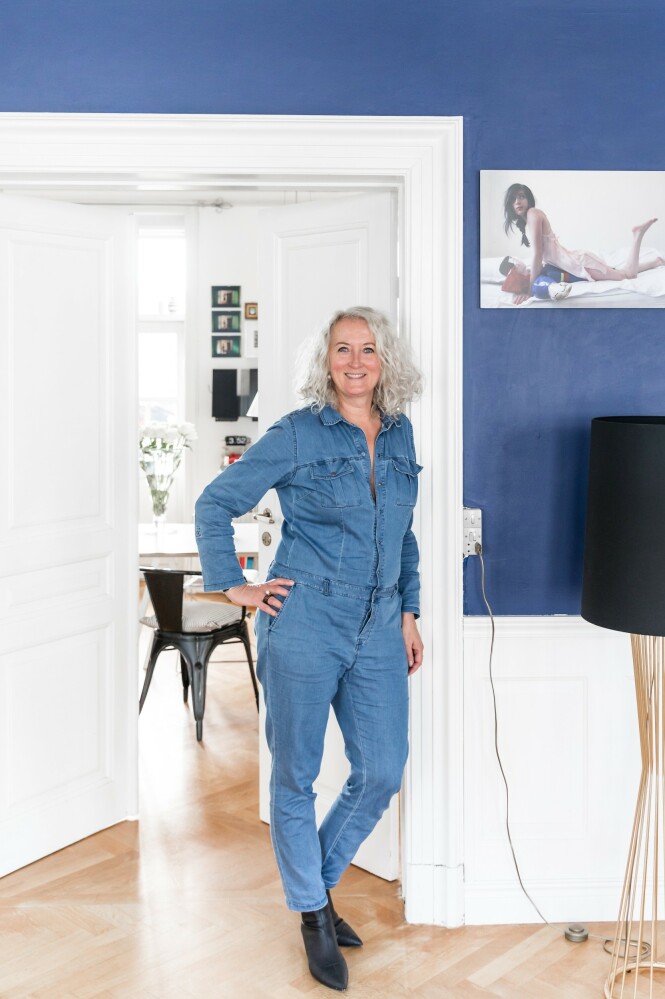 Her står Mai-Britt i dør åpningen mellom stue og kjøkken. Ved siden av henne står messinglampen Tulip designet av Autoban. FOTO: Julie Wittrup og Mikkel Dahlstrøm/Another Studio Her står Mai-Britt i dør åpningen mellom stue og kjøkken. Ved siden av henne står messinglampen Tulip designet av Autoban. FOTO: Julie Wittrup og Mikkel Dahlstrøm/Another Studio