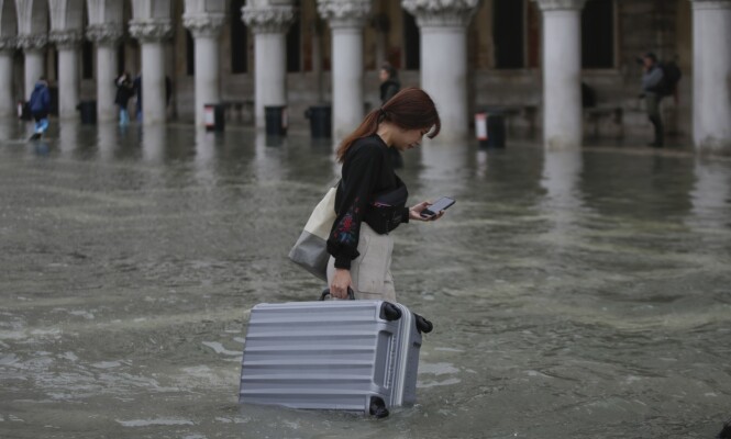 <strong>VASSER:</strong> Turister vasser gjennom vannmassene i Venezia og forsøker å redde koffertene sine. Foto: Luca Bruno / AP / NTB Scanpix <strong>VASSER:</strong> Turister vasser gjennom vannmassene i Venezia og forsøker å redde koffertene sine. Foto: Luca Bruno / AP / NTB Scanpix