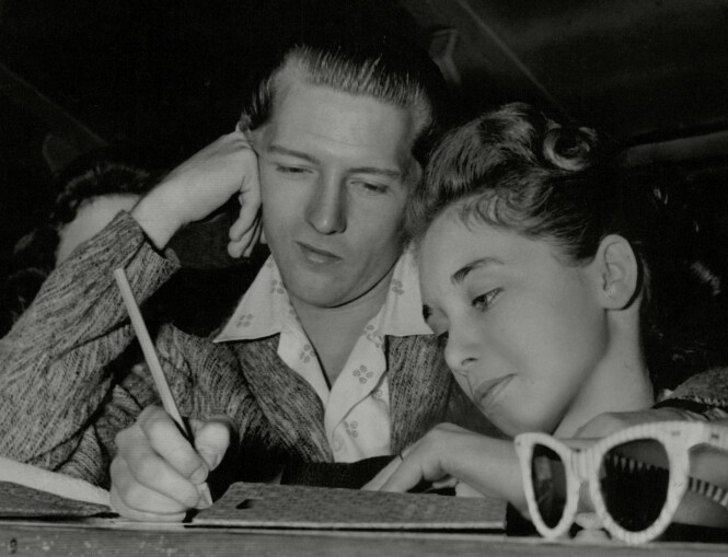 FORELSKET: Jerry Lee Lewis kaster et forelsket blikk mot kona Myra, som skriver i noe som kan se ut som kladdebøker. Bildet er tatt i 1958. FOTO: NTB scanpix FORELSKET: Jerry Lee Lewis kaster et forelsket blikk mot kona Myra, som skriver i noe som kan se ut som kladdebøker. Bildet er tatt i 1958. FOTO: NTB scanpix