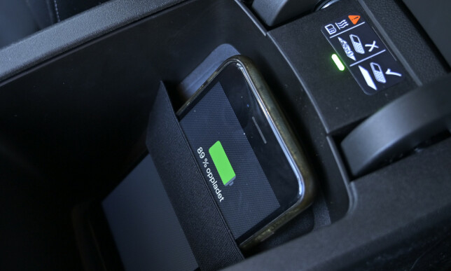 STRIKK: Du finner en nødløsning for trådløs lading under armlenet. Telefonen må være stående og holdes inntil laderen med en strikk. Foto: Rune M. Nesheim STRIKK: Du finner en nødløsning for trådløs lading under armlenet. Telefonen må være stående og holdes inntil laderen med en strikk. Foto: Rune M. Nesheim