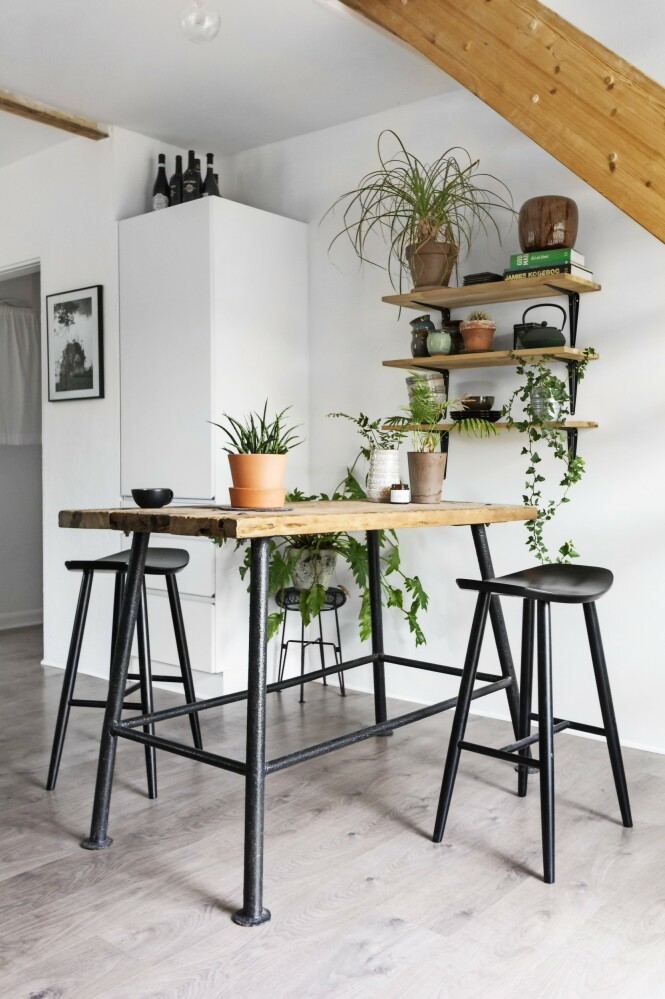 I et hjørne av kjøkkenet under trappen til annen etasje tar Fie og Jonas ofte morgenkaffen. Det høye plankebordet og barstolene skaper et uhøytidelig uttrykk. Tips! Svart, hvitt, metall og røft treverk. Sammen med grønne planter skaper det en rustikk og samtidig moderne stil. FOTO: Mettemaje Skøtt og Camilla Skøtt I et hjørne av kjøkkenet under trappen til annen etasje tar Fie og Jonas ofte morgenkaffen. Det høye plankebordet og barstolene skaper et uhøytidelig uttrykk. Tips! Svart, hvitt, metall og røft treverk. Sammen med grønne planter skaper det en rustikk og samtidig moderne stil. FOTO: Mettemaje Skøtt og Camilla Skøtt