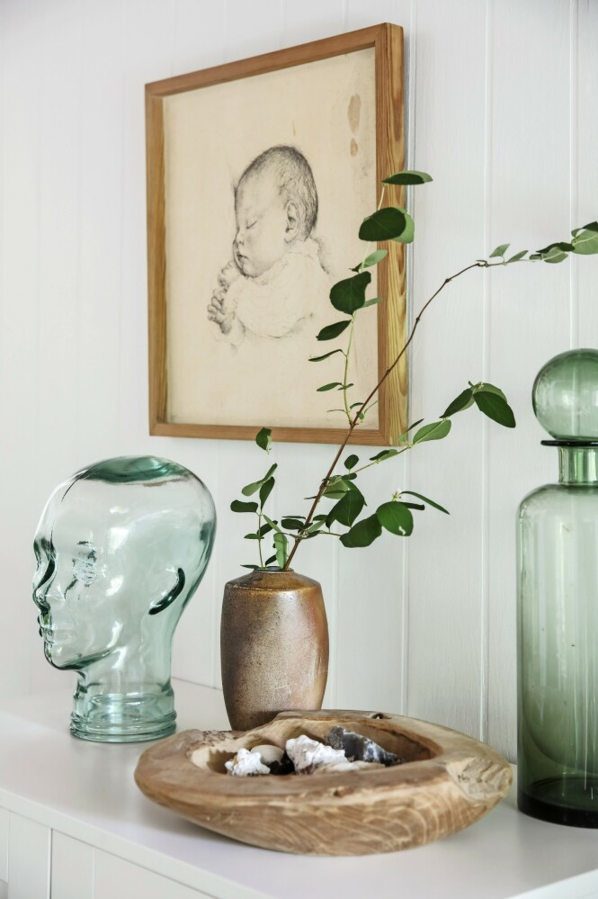Sett grønt glass sammen med ting i tre og keramikk for å lette uttrykket. Tegning, glasshode og treskål er loppfunn. Den brune vasen er av keramikeren Sten Børsting, mens karaffelen er fra House Doctor. FOTO: Christina Kayser O. Sett grønt glass sammen med ting i tre og keramikk for å lette uttrykket. Tegning, glasshode og treskål er loppfunn. Den brune vasen er av keramikeren Sten Børsting, mens karaffelen er fra House Doctor. FOTO: Christina Kayser O.