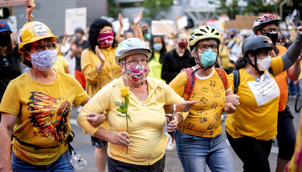 WALL OF MOMS: Norma Lewis (med blomst) og andre demonstranter som kaller seg "Wall of Moms" protesterer mot de føderale styrkene i Portland. Foto: AP Photo/Noah Berger WALL OF MOMS: Norma Lewis (med blomst) og andre demonstranter som kaller seg "Wall of Moms" protesterer mot de føderale styrkene i Portland. Foto: AP Photo/Noah Berger